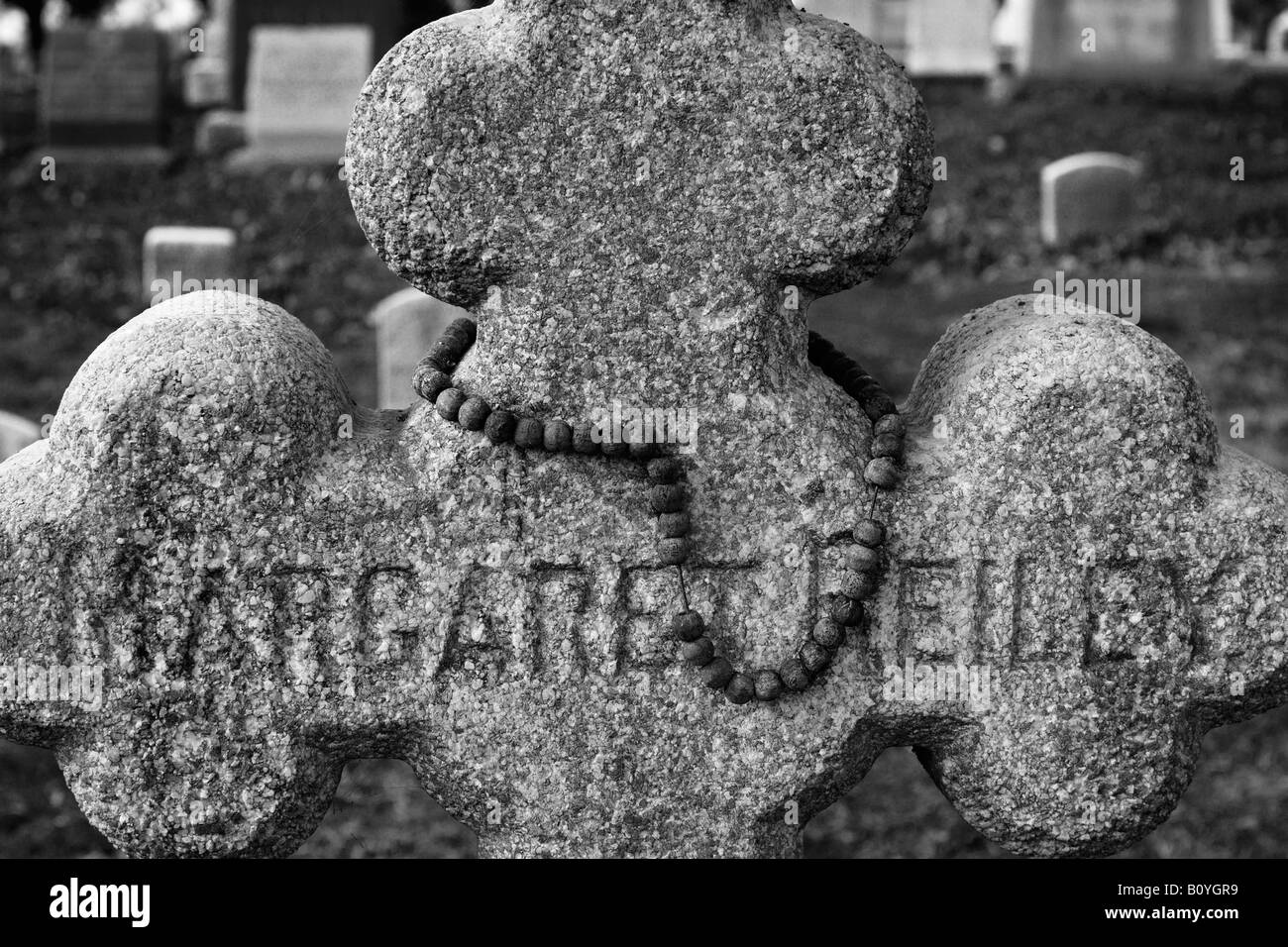 Un vecchio cimitero lapide per Margaret Reiley con un rosario spiovente drappeggiati intorno ad esso Foto Stock