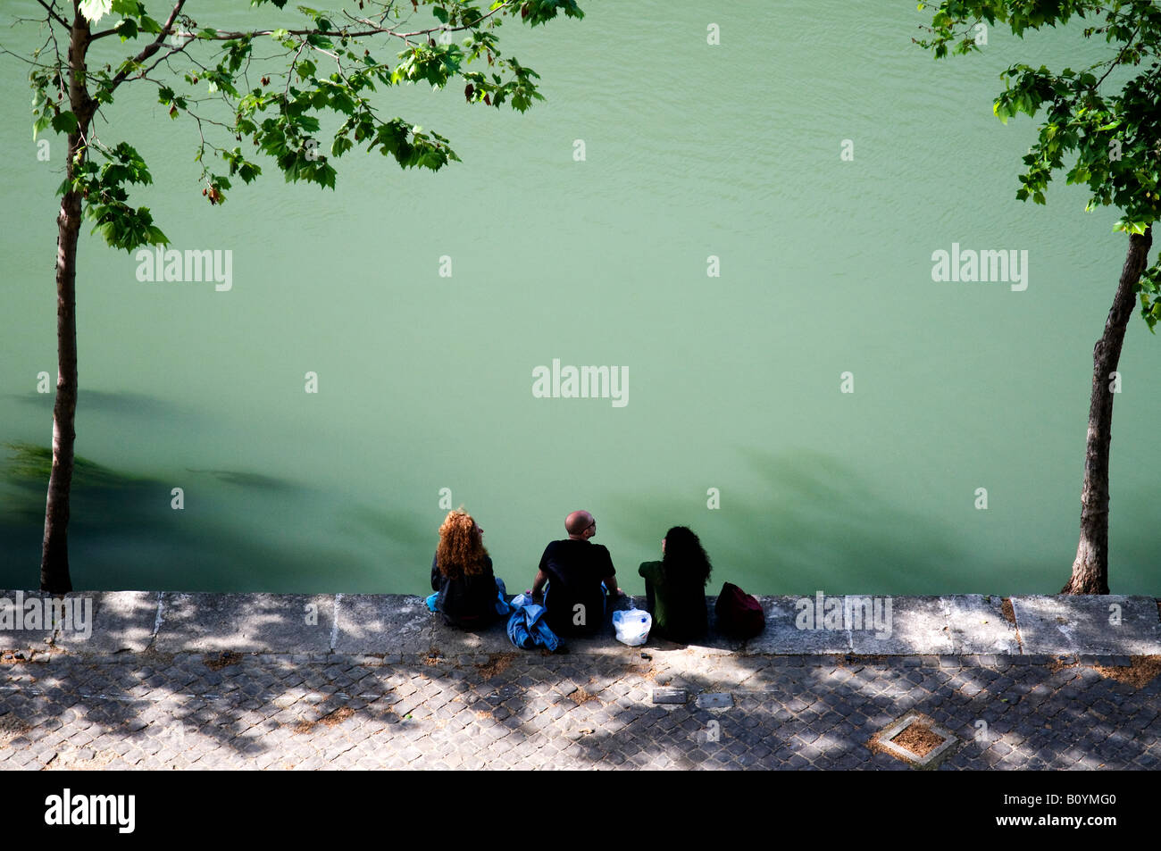 Turisti che si siedono sulla riva del fiume Tevere a Roma, Italia Foto Stock