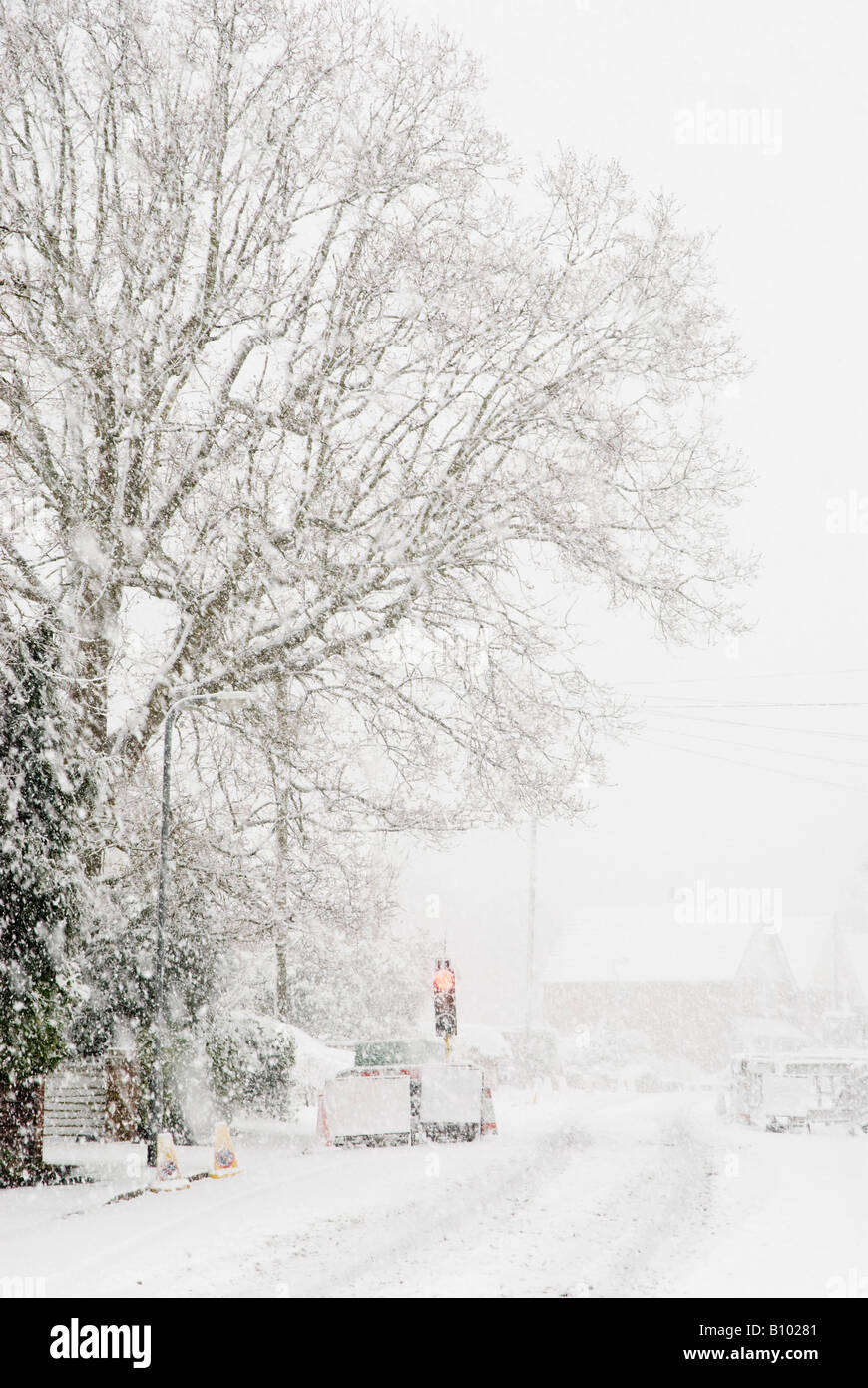 Nevicata sulla strada tranquilla con opere stradali e semaforo rosso Foto Stock