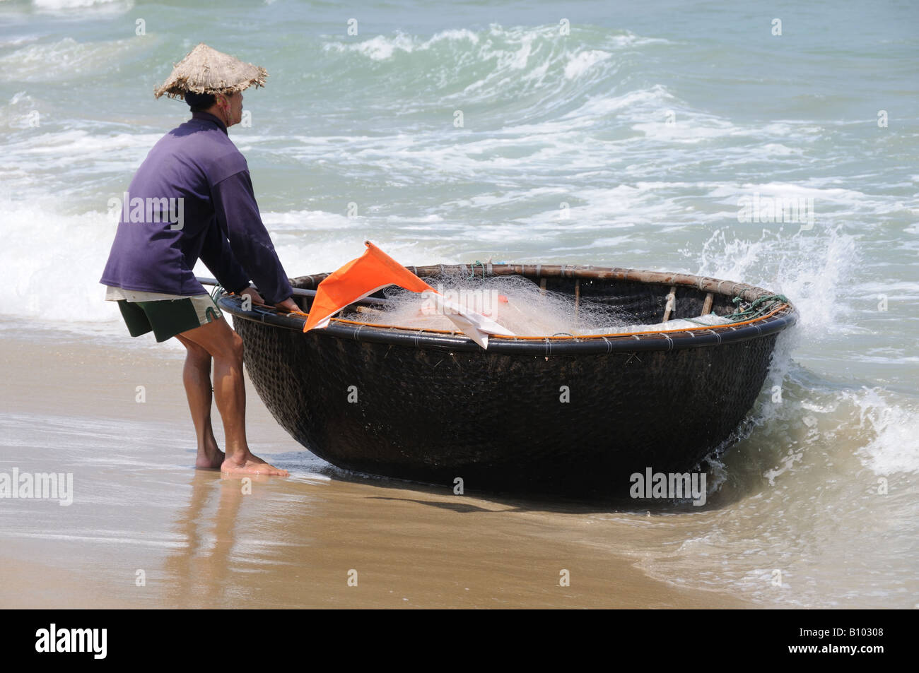 Pescatore con coracolo tradizionale vietnamita o barca a cesto tessuta da bambù Cua dai Beach Vietnam Foto Stock