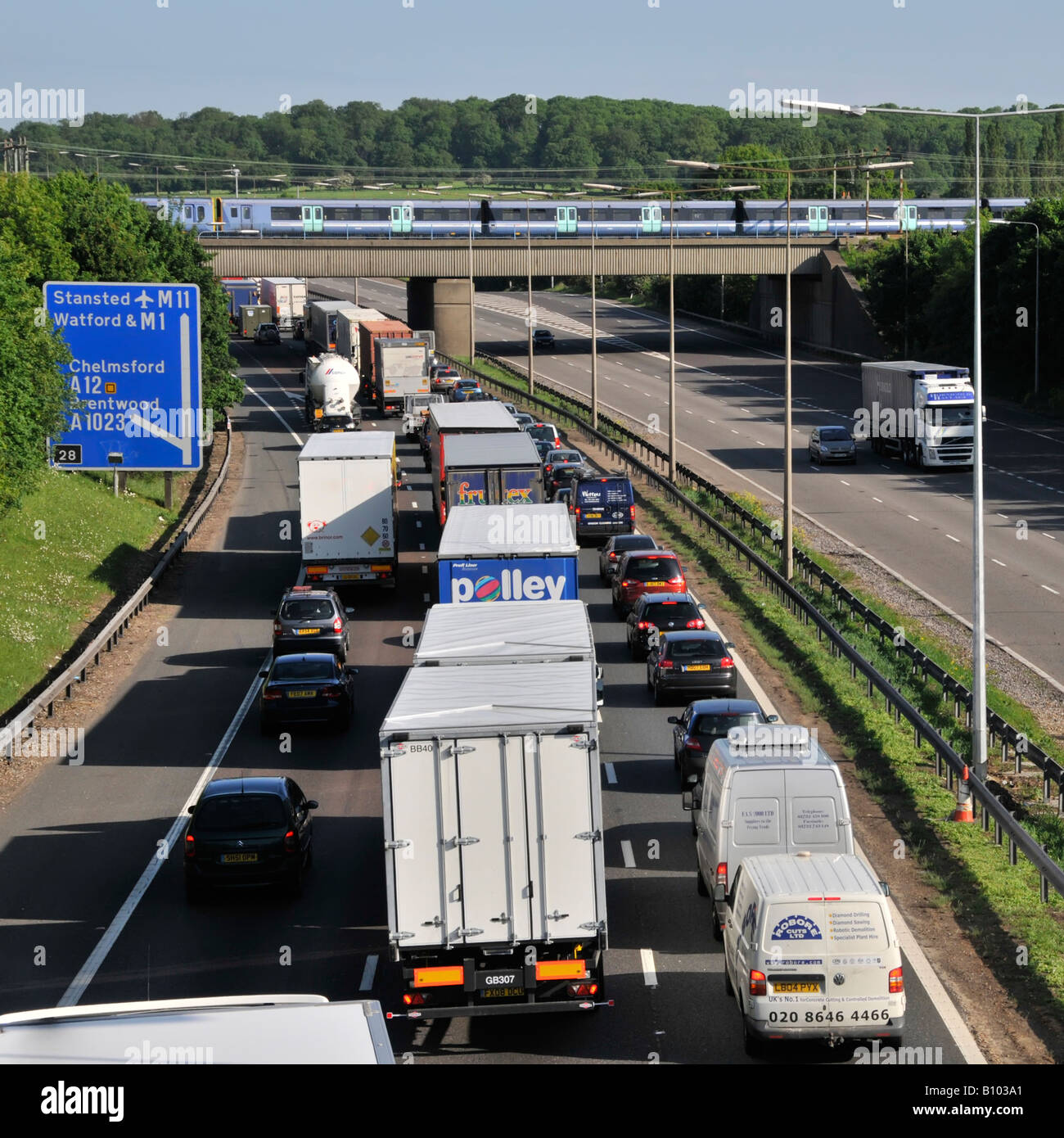 Scelta di trasporto autostrada M25 da naso a coda traffico lento guardando treno veloce passeggeri sul ponte ferroviario svincolo 28 Brentwood Essex Inghilterra Regno Unito Foto Stock