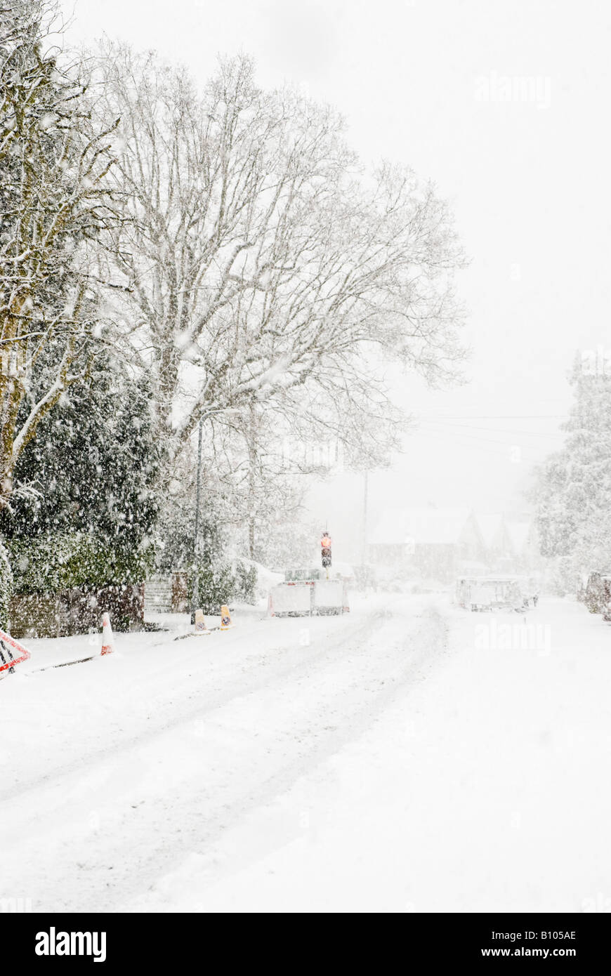 Nevicata sulla strada tranquilla con opere stradali e semaforo rosso Foto Stock