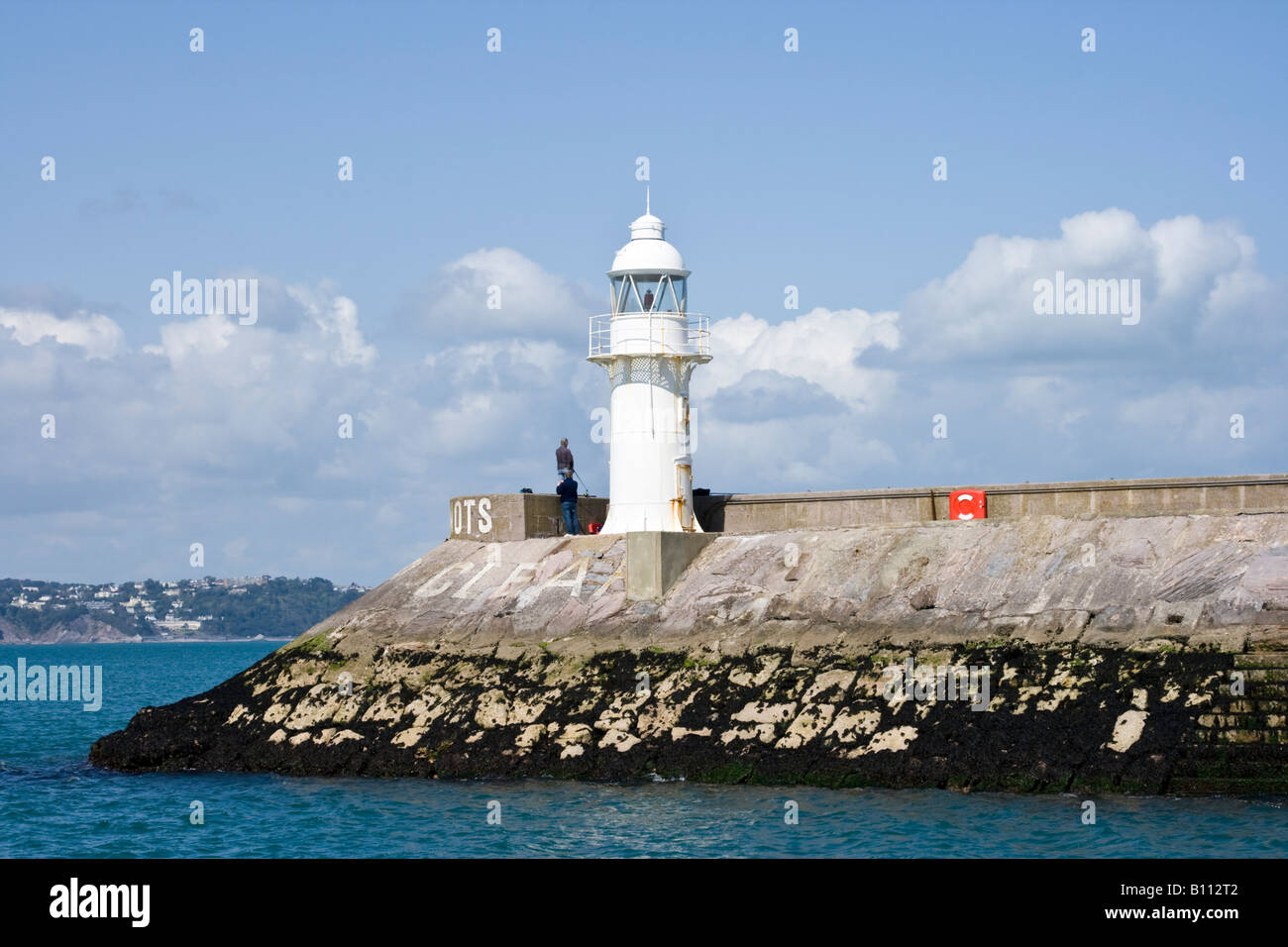 Faro di ingresso al porto di Brixham con Torquay in background Foto Stock