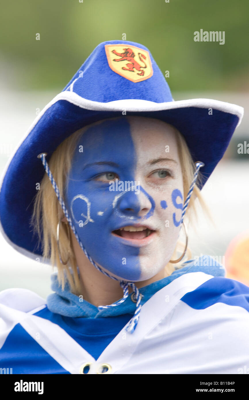 Calcio femminile tifoso di calcio nel suo team di colori blu e bianco con un cappello da cowboy sulla faccia dipinta e una bandiera Scozia UK Foto Stock