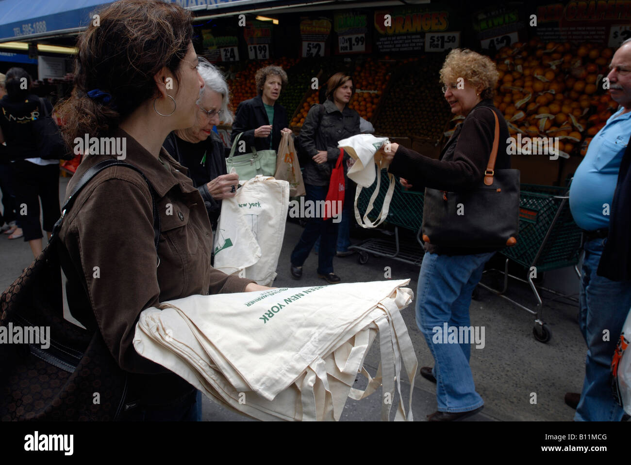 Volontari nella parte anteriore del fairway supermercato in New York dare via riutilizzabile sacchi di tela per gli amanti dello shopping per sostituire i sacchetti di plastica Foto Stock