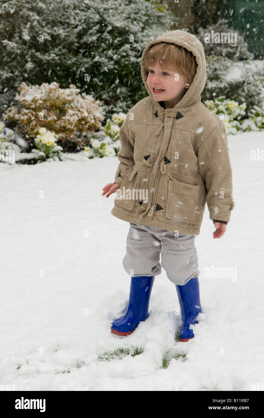 ragazzo, bambino, in piedi sulla neve vestito con abiti caldi che sembrano felici di essere fuori Foto Stock
