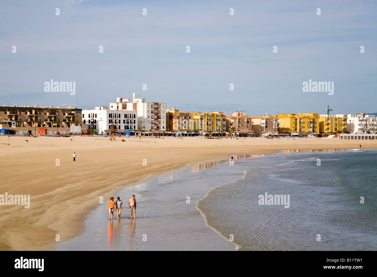Alcuni turisti si godono una passeggiata lungo la spiaggia di Barbate - Playa de Barbate - sotto il sole del tardo pomeriggio. Playa de Barbate, Barbate, Cádiz, Andalucía, Spagna. Foto Stock