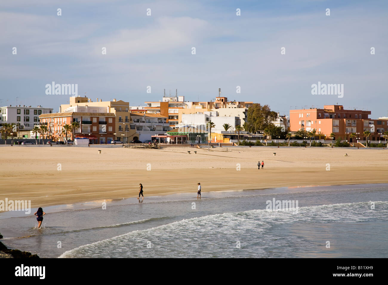 Alcuni turisti si godono una passeggiata lungo la spiaggia di Barbate - Playa de Barbate - sotto il sole del tardo pomeriggio. Playa de Barbate, Barbate, Cádiz, Andalucía, Spagna. Foto Stock