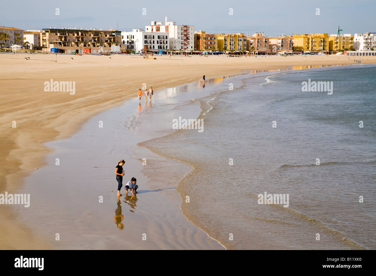 Alcuni turisti si godono una passeggiata lungo la spiaggia di Barbate - Playa de Barbate - sotto il sole del tardo pomeriggio. Playa de Barbate, Barbate, Cádiz, Andalucía, Spagna. Foto Stock