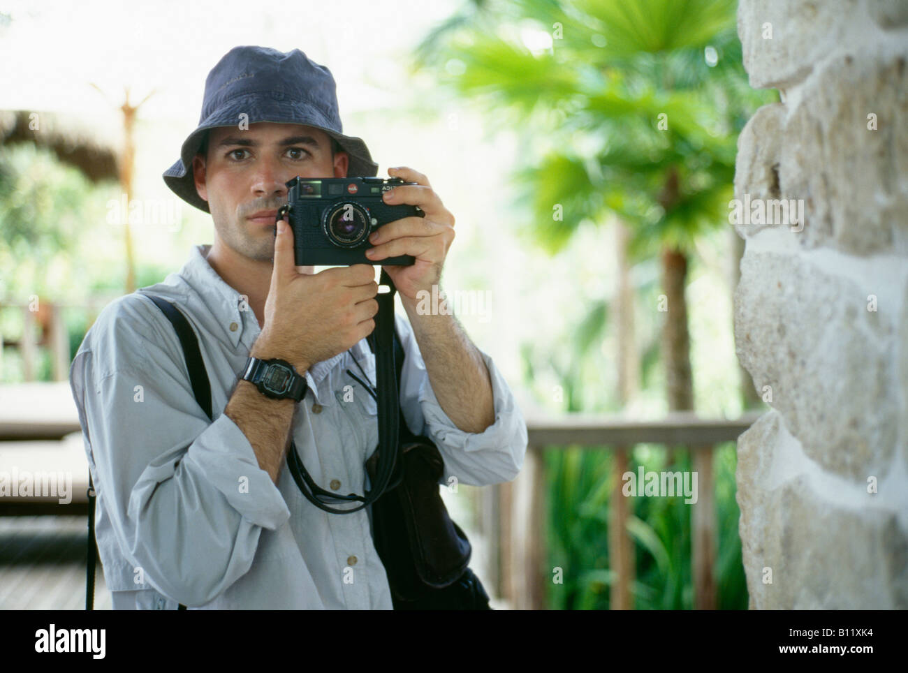 Un giovane fotografo con la sua macchina fotografica tra la lussureggiante vegetazione in Indonesia. Foto Stock