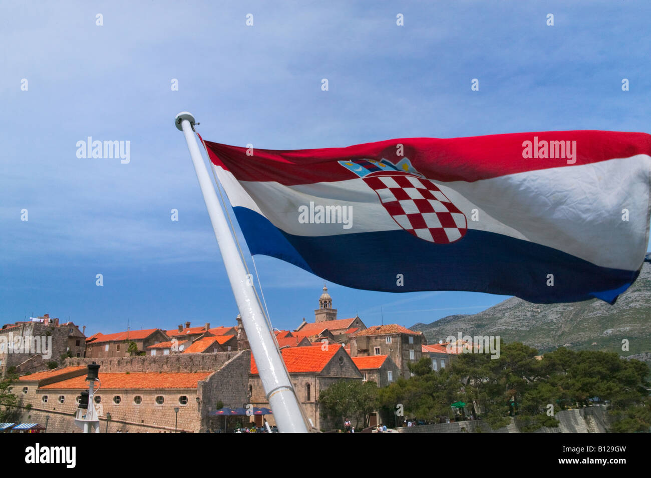Barca con bandiera nazionale avvicinandosi Korcula nel mare Adriatico Croazia Foto Stock