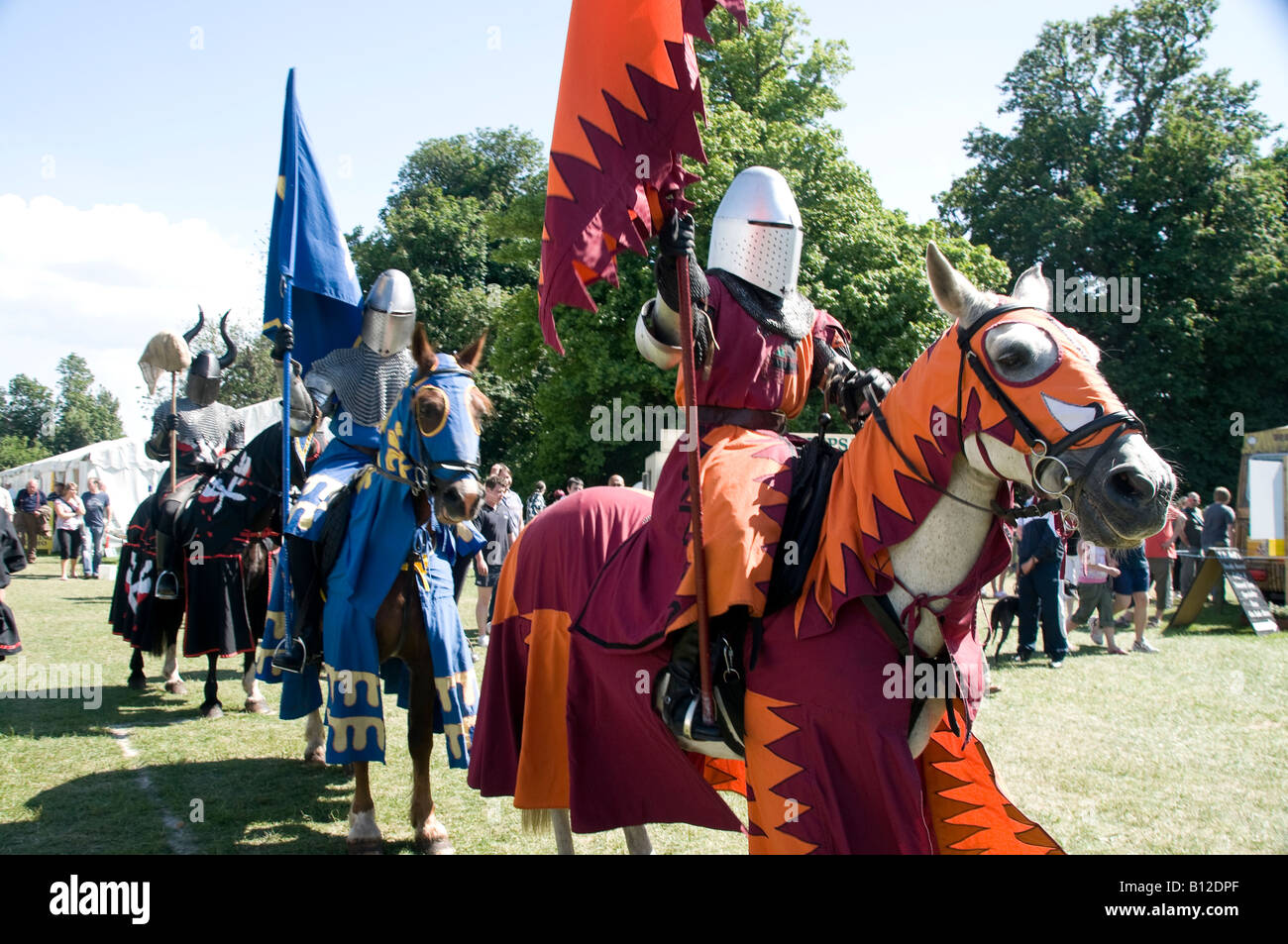Cavaliere a cavallo con armatura, portando i colori (flag) durante una fiera medievale rievocazione Foto Stock