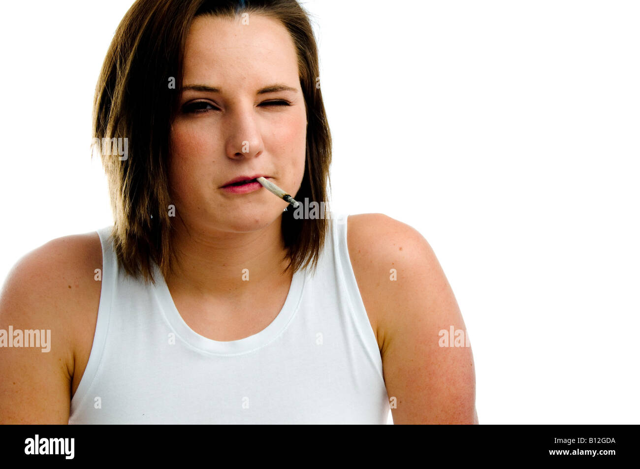 Moody ribelle cercando inglese diciannovenne ragazza adolescente indossando bianco Gilet fumatori arrotolate a mano sigaretta, REGNO UNITO Foto Stock