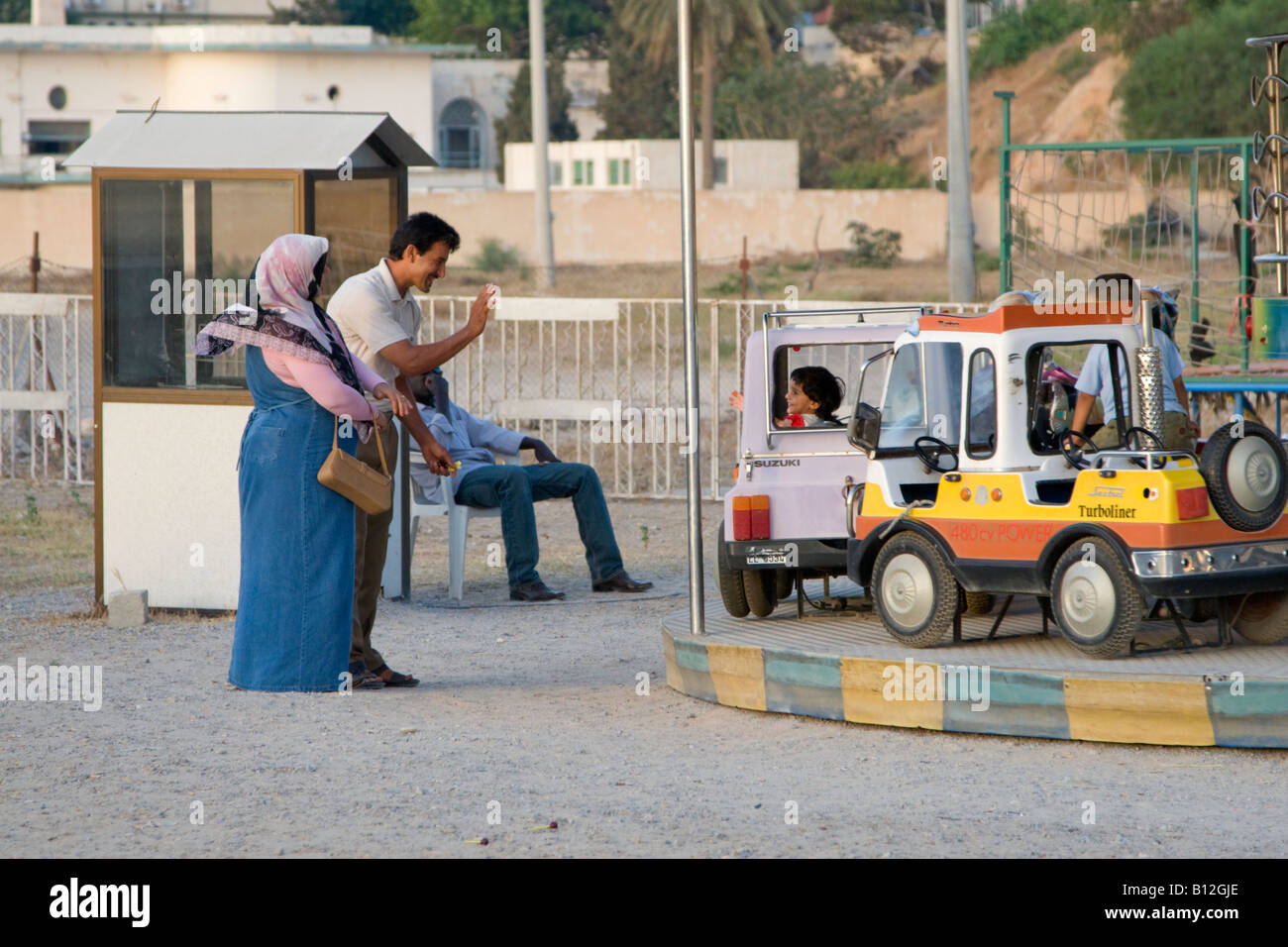 Tripoli in Libia Africa del Nord i genitori libico sventolano al bambino sul parco dei divertimenti di corsa Foto Stock