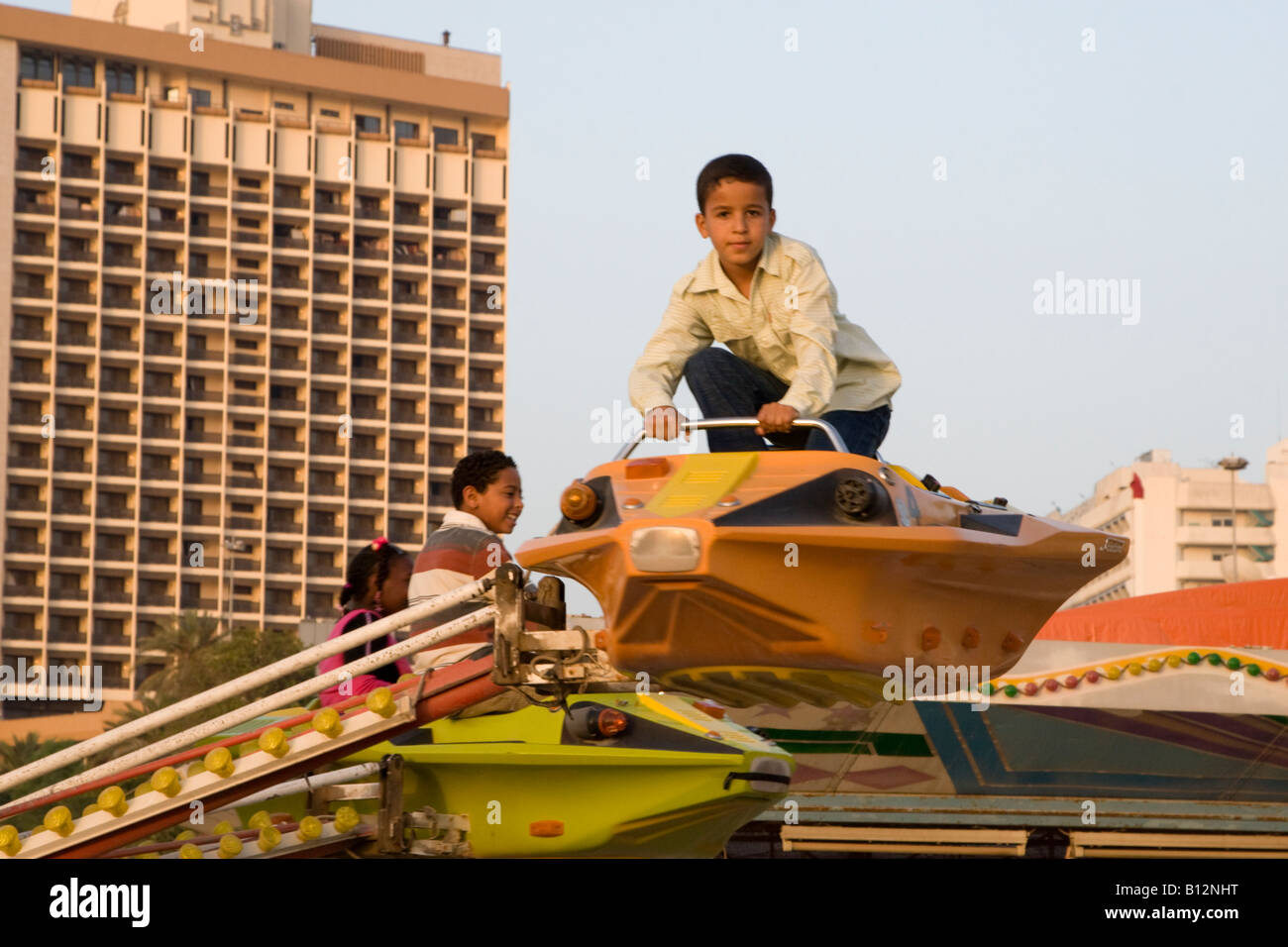 Tripoli, Libia, Nord Africa. I bambini sul parco dei divertimenti di Ride Boy in piedi senza cintura di sicurezza Foto Stock