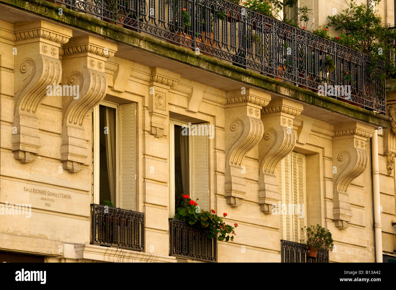 Facciata di un edificio di Parigi con balconi e finestre con fiori in primavera. Foto Stock