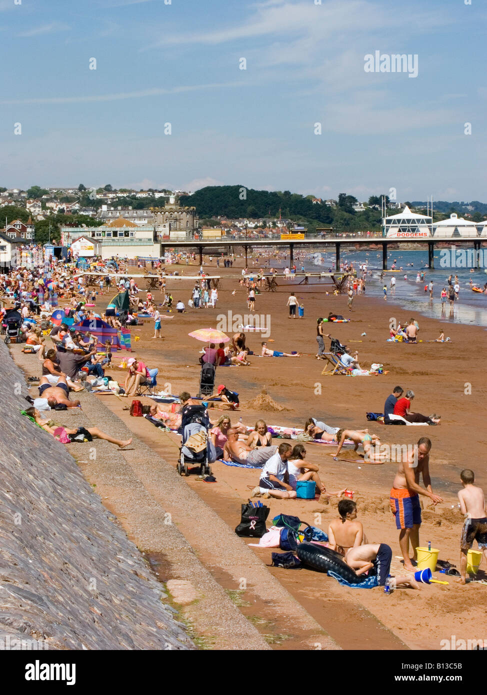 I turisti godono del sole estivo sulla spiaggia e sul molo per il tempo libero. Paignton, Devon Regno Unito Foto Stock