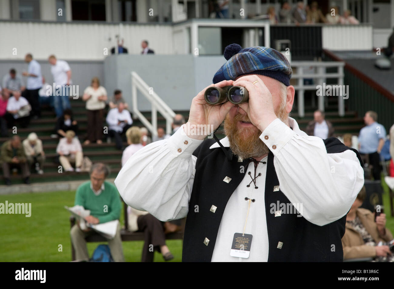 Scozzese uomo che alleva tartan plaid con Binocolo all'ippodromo di Perth, Gold Cup Day, Tayside, Scozia uk Foto Stock