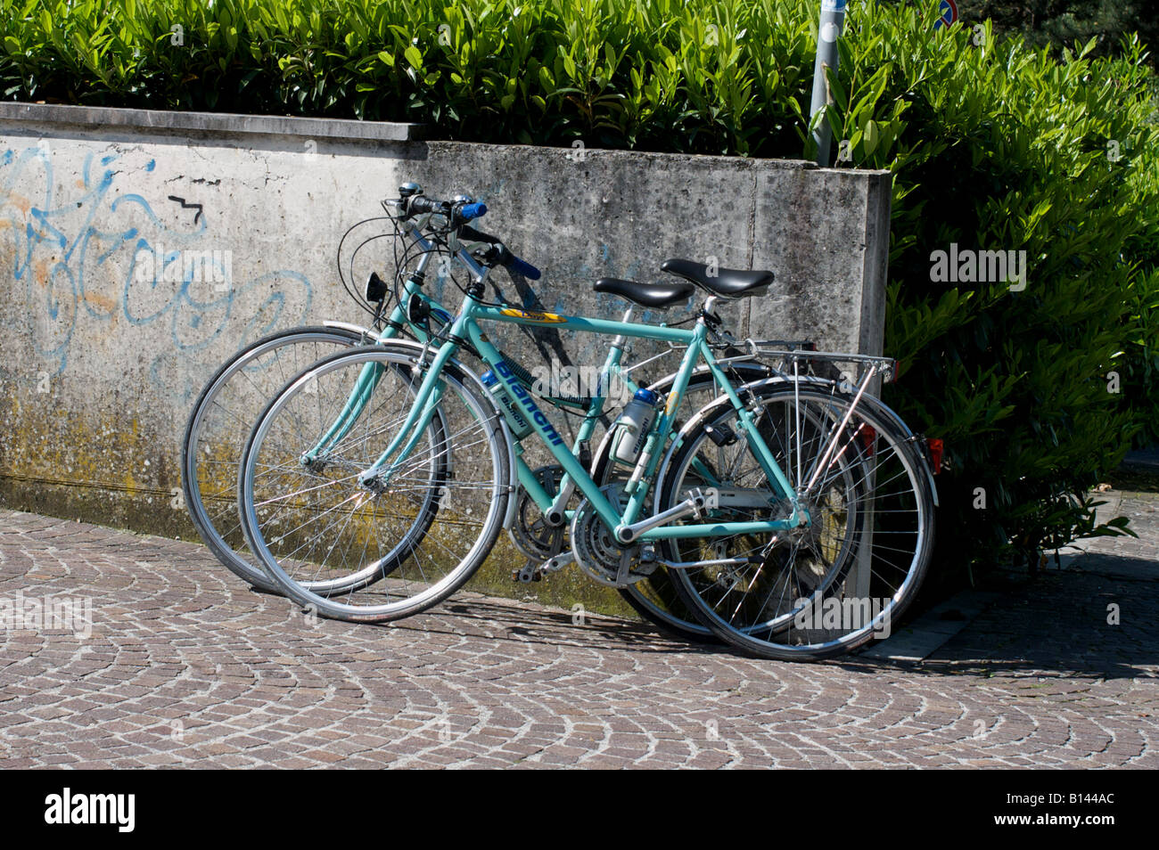 Biciclette appoggiata contro un muro basso in Cormons, una piccola città in Italia Foto Stock