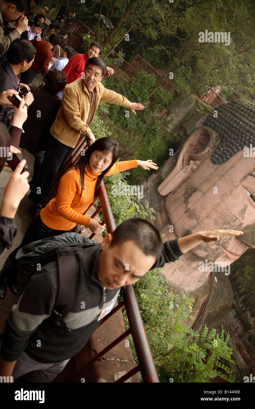 I turisti cinesi tenere le loro braccia in fuori rispetto al Buddha gigante Foto Stock