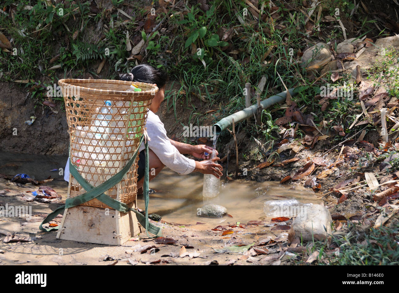 Vietnamita donna riempire le bottiglie di acqua pulita da una nuova alimentazione idrica Highlands centrali Vietnam Foto Stock