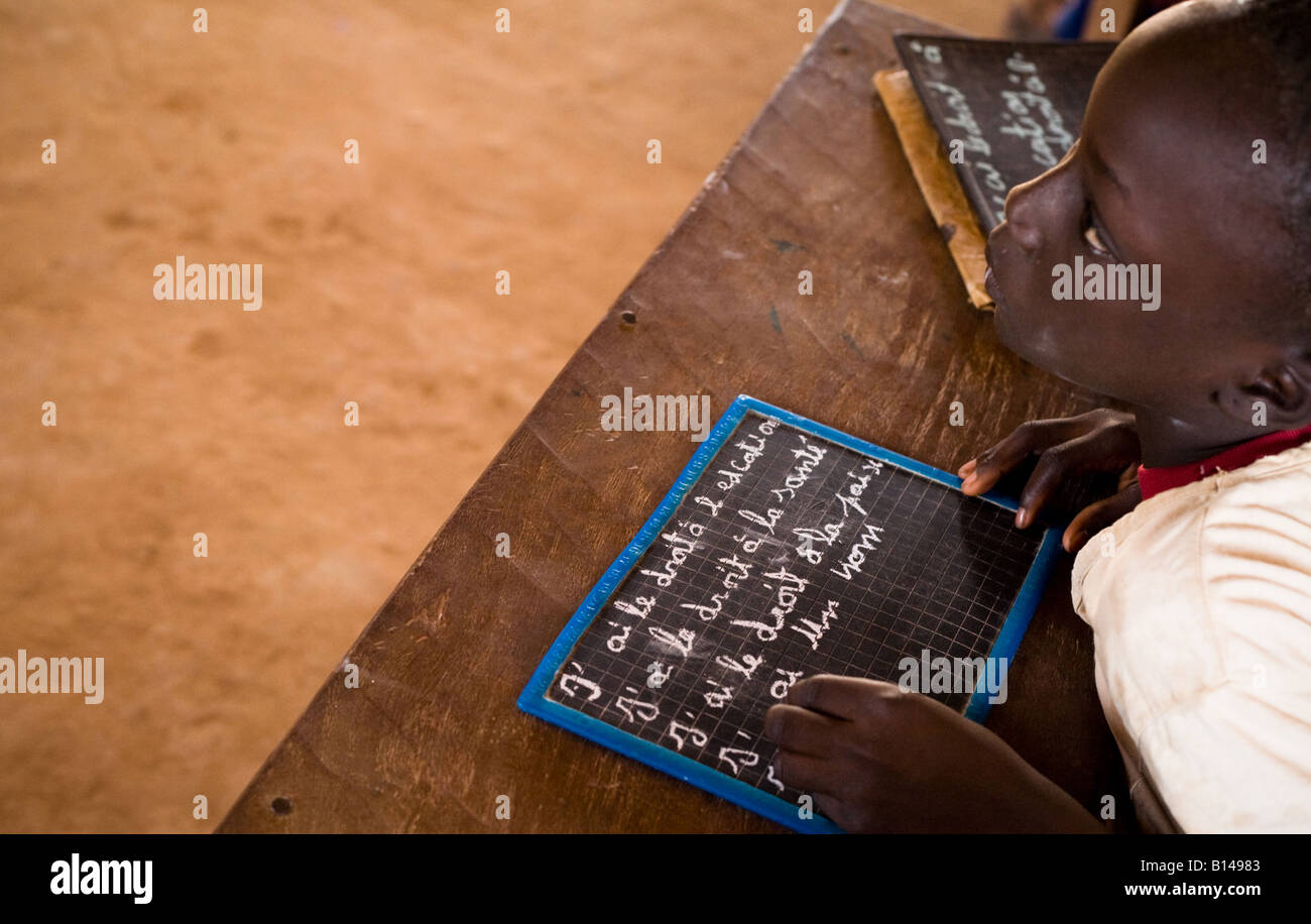 Una ragazza scrive il basic i diritti dei bambini sul suo chalk board Foto Stock
