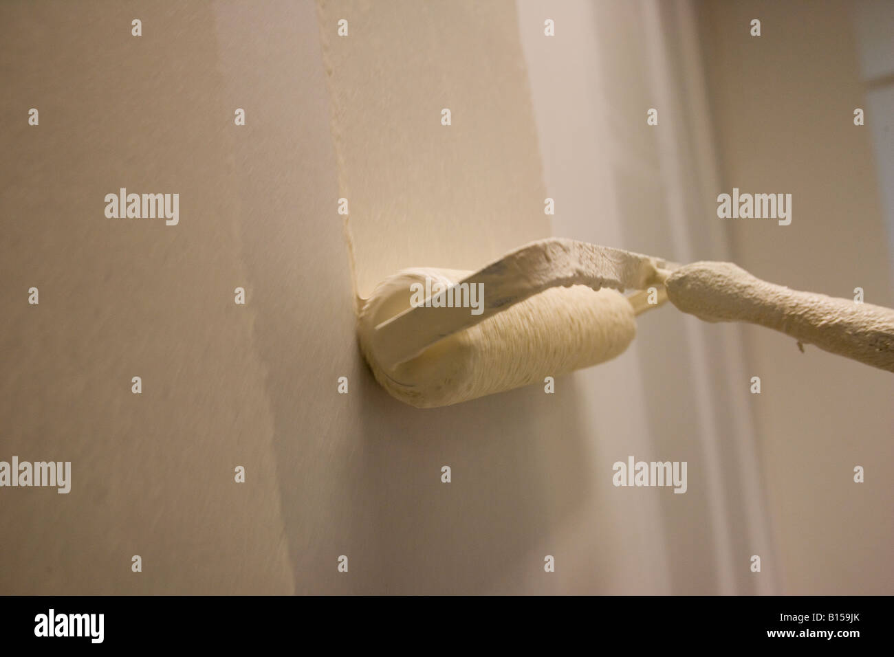 Un decoratore dipinge la parete con spessore della vernice in un costruito di recente costruzione di ufficio. Foto Stock