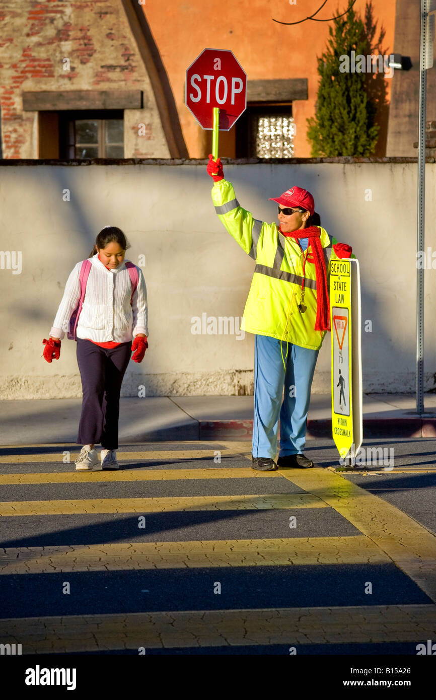 Ispanico attraversamento scuola guard controlla il traffico della strada come California del sud gli studenti della scuola elementare e genitori arrivano in AM Foto Stock