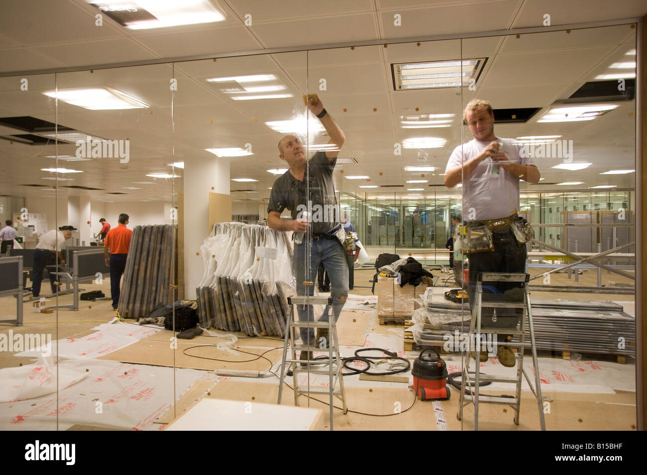 Un operaio pulisce un vetro parition in un costruito di recente costruzione di ufficio. Foto Stock