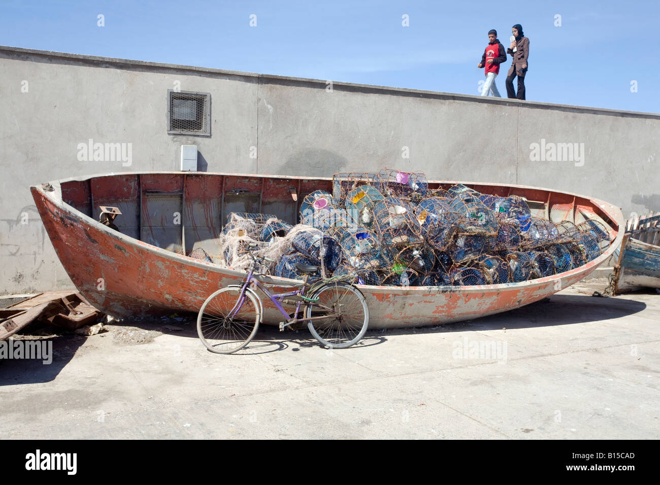 Giovane camminando lungo la parete del mare. Porto di Essaouira, Marocco Foto Stock