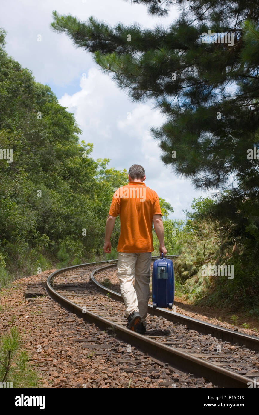 Uomo che cammina su una ferrovia con la sua valigia Foto Stock