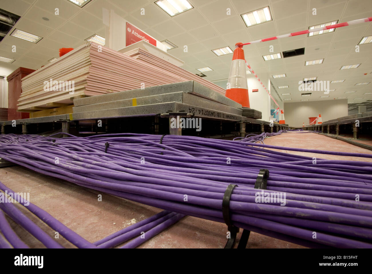 Fasci di cavi attraverso il pavimento sopraelevato di un costruito di recente costruzione di ufficio. Foto Stock