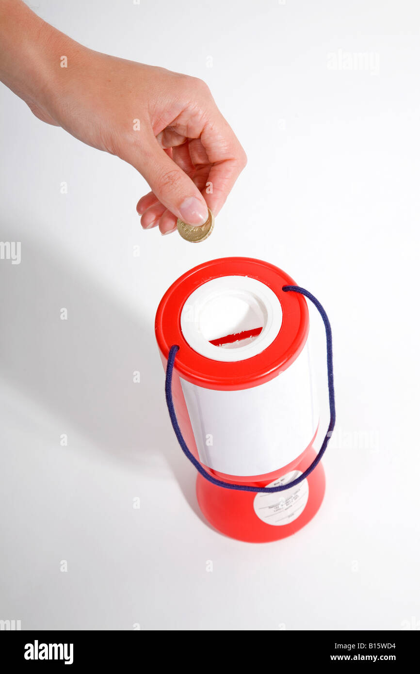 Red charity box stagno di raccolta con la mano dare i soldi dal di sopra contro uno sfondo bianco Foto Stock