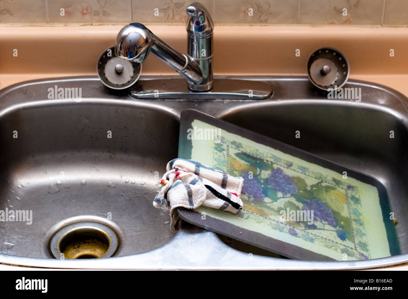 Un lavaggio rag siede sullaparte superiore di una lavata tagliere in un lavandino Foto Stock
