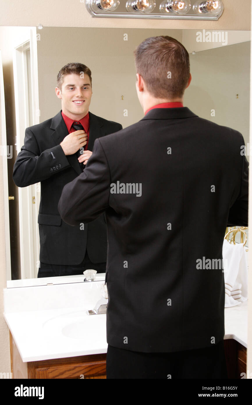 Fotografia di stock di un giovane uomo regolando la cravatta allo specchio Foto Stock