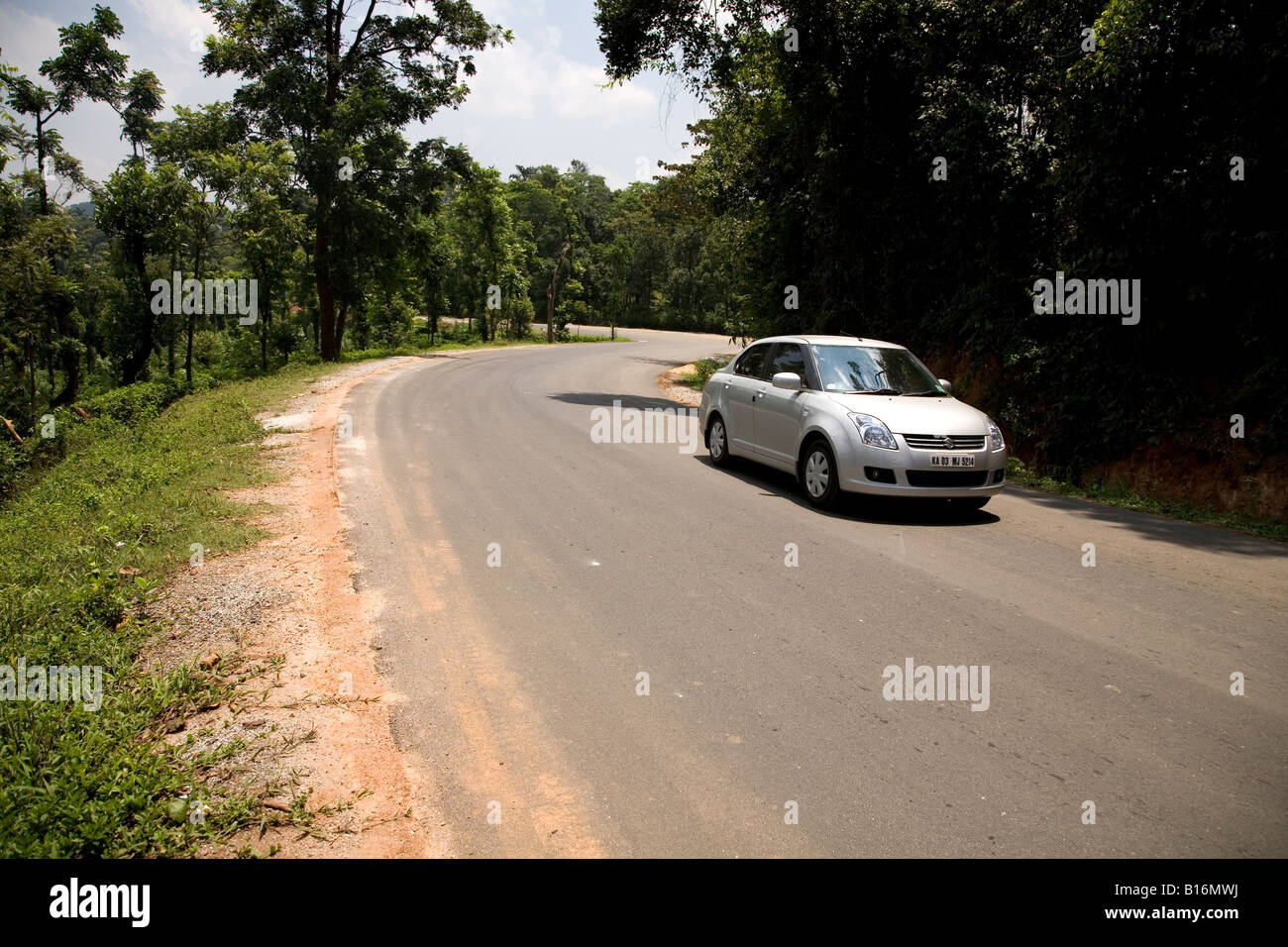 Una vettura spazia attraverso la S curve e folta vegetazione e il bosco della i Ghati Occidentali. Foto Stock