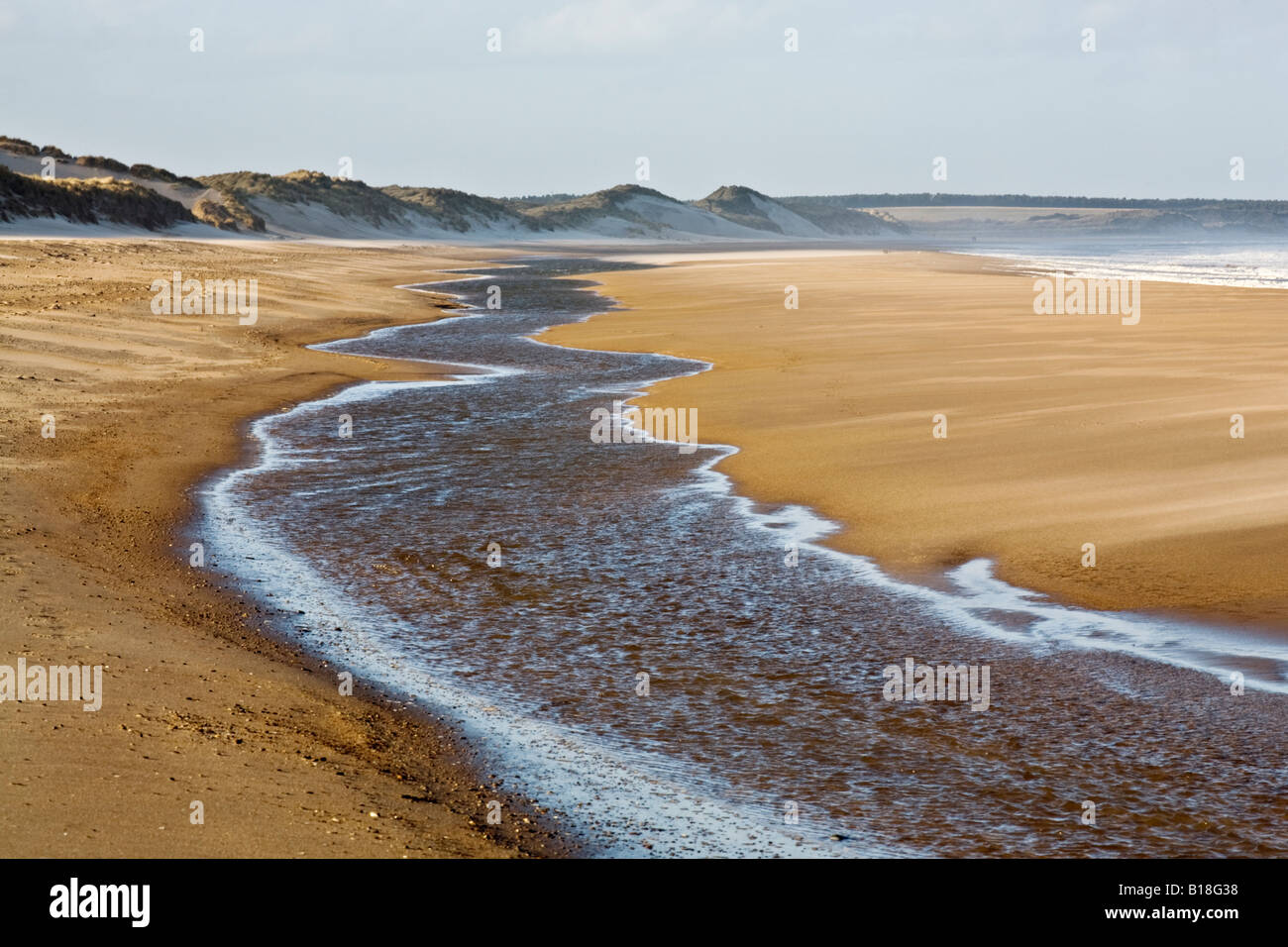 Fiume che scorre lungo la spiaggia vicino al tideline a Druridge Bay sulla costa Northumbrian, Northumberland, Inghilterra Foto Stock