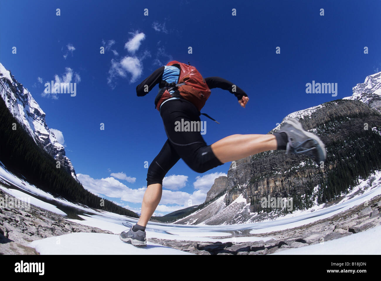 Una giovane donna trail running nella primavera vicino alle rive del Lago Moraine al Lago Louise, il Parco Nazionale di Banff, Alberta, Canada. Foto Stock