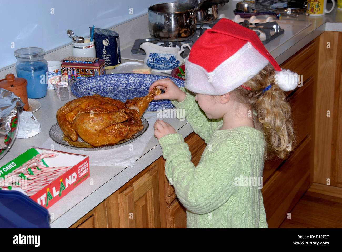 Bambina cercando di prendere un pezzo di pollo a una festa di Natale Foto Stock