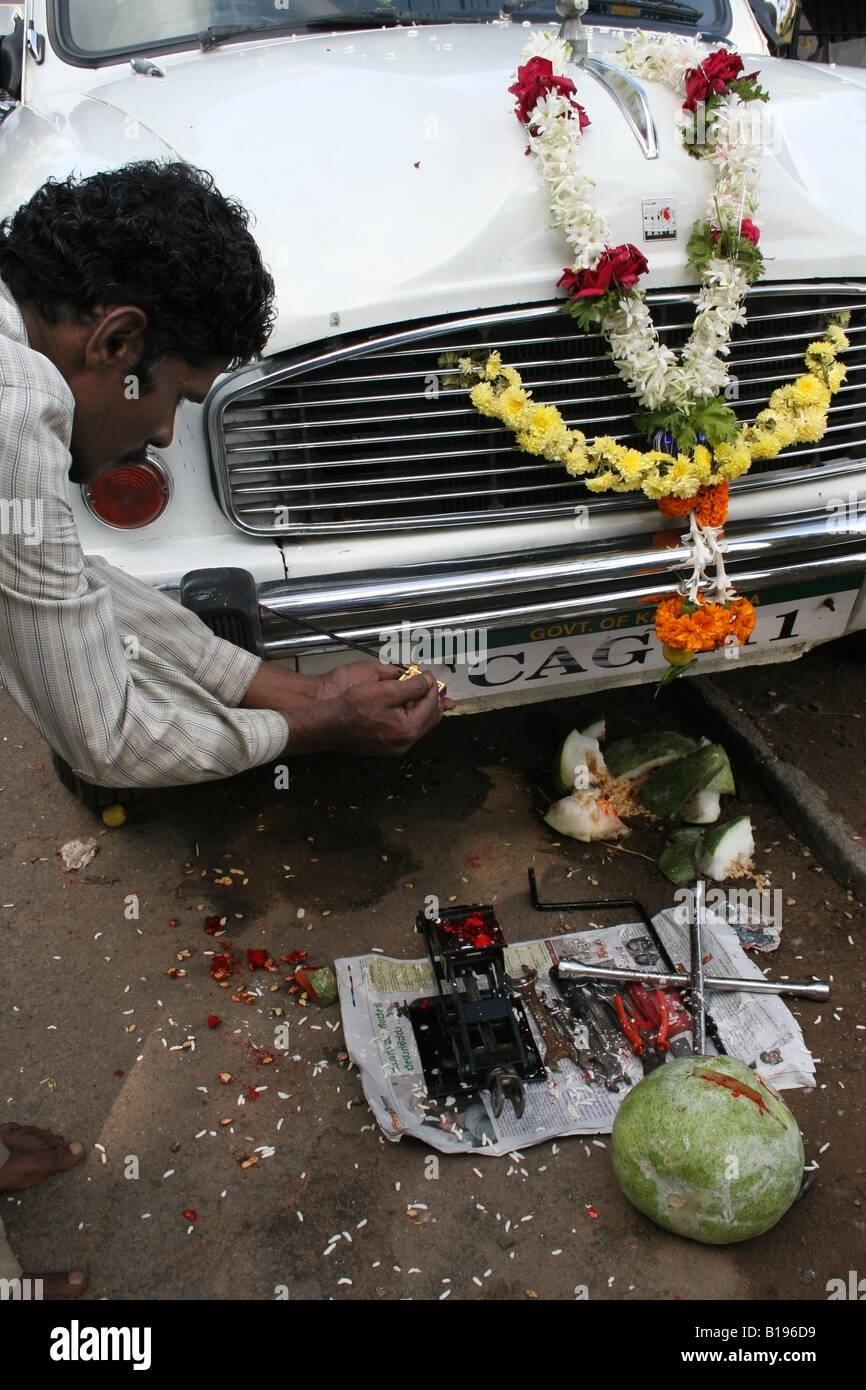 Luci uomo incenso sulla sua vettura dopo aver decorato con fiori per Vishwakarma Ayudha Puja, India Foto Stock