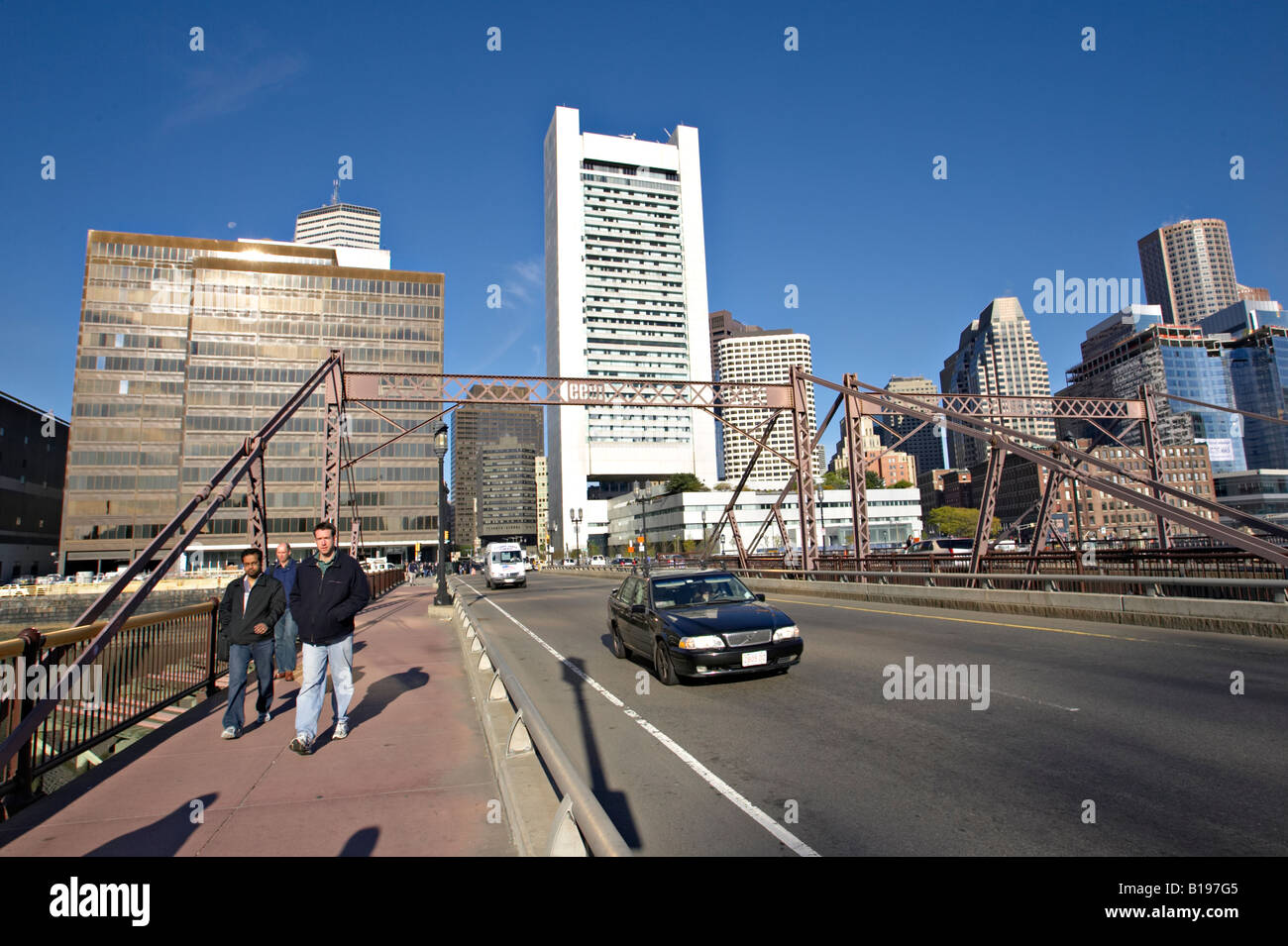 MASSACHUSETTS Boston Federal Reserve building and skyline viewed from bridge to Seaport District pedestrians crossing bridge Foto Stock