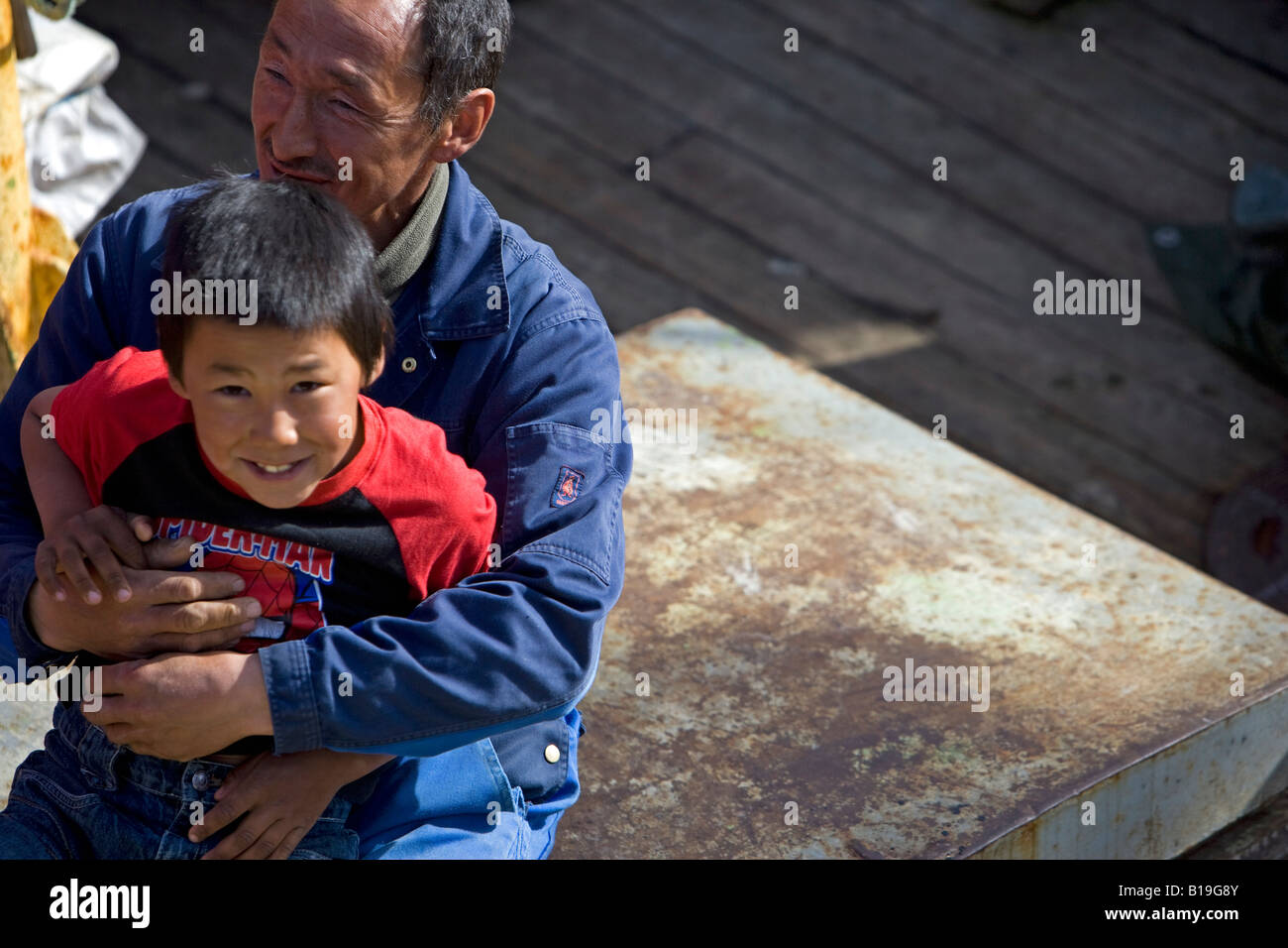 La Groenlandia, Ilulissat. Un padre di estrazione Inuit gioca con suo figlio sul ponte di una barca da pesca nella zona portuale. Foto Stock