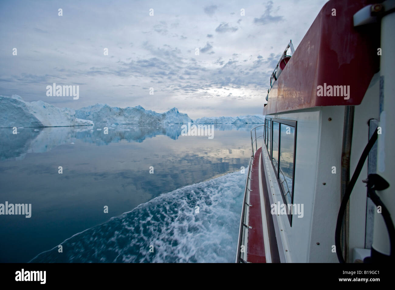 La Groenlandia, Ilulissat, Sito Patrimonio Mondiale dell'UNESCO icebergs. Barca a vela attraverso il icebergs a mezzanotte con il cielo ancora la luce. Foto Stock