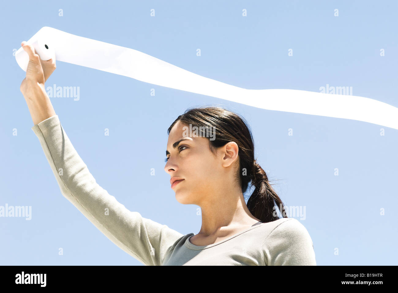 Donna che mantiene fino carta igienica rotolo all'aperto, lo streaming di carta nel vento, a basso angolo di visione Foto Stock