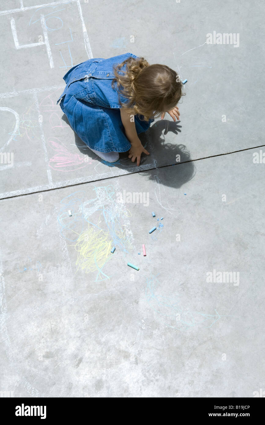 Ragazza che gioca con il gesso, curvò oltre, ad alto angolo di visione Foto Stock