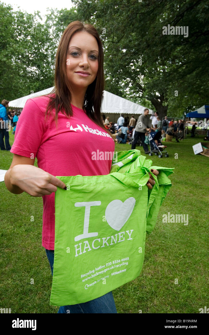 Giovane donna dando via verde utilizzabile nuovamente borse di stoffa con I Love Hackney su di essi Foto Stock
