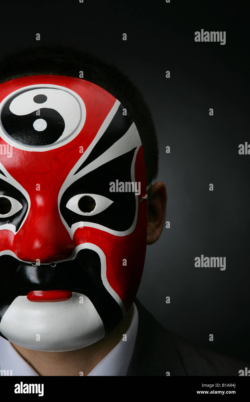 Businessman cinesi indossando un'opera Cinese maschera Foto Stock