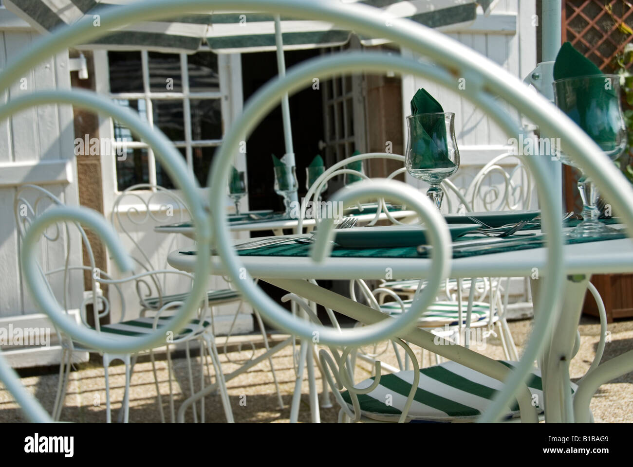 Foto di stock di un ristorante tavola su un nenti la partecipazione presa attraverso il retro di un ferro battuto sedia Foto Stock