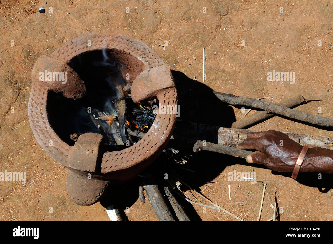 Donna africana che accende il fuoco in una stufa di fango in un villaggio in Malawi Foto Stock