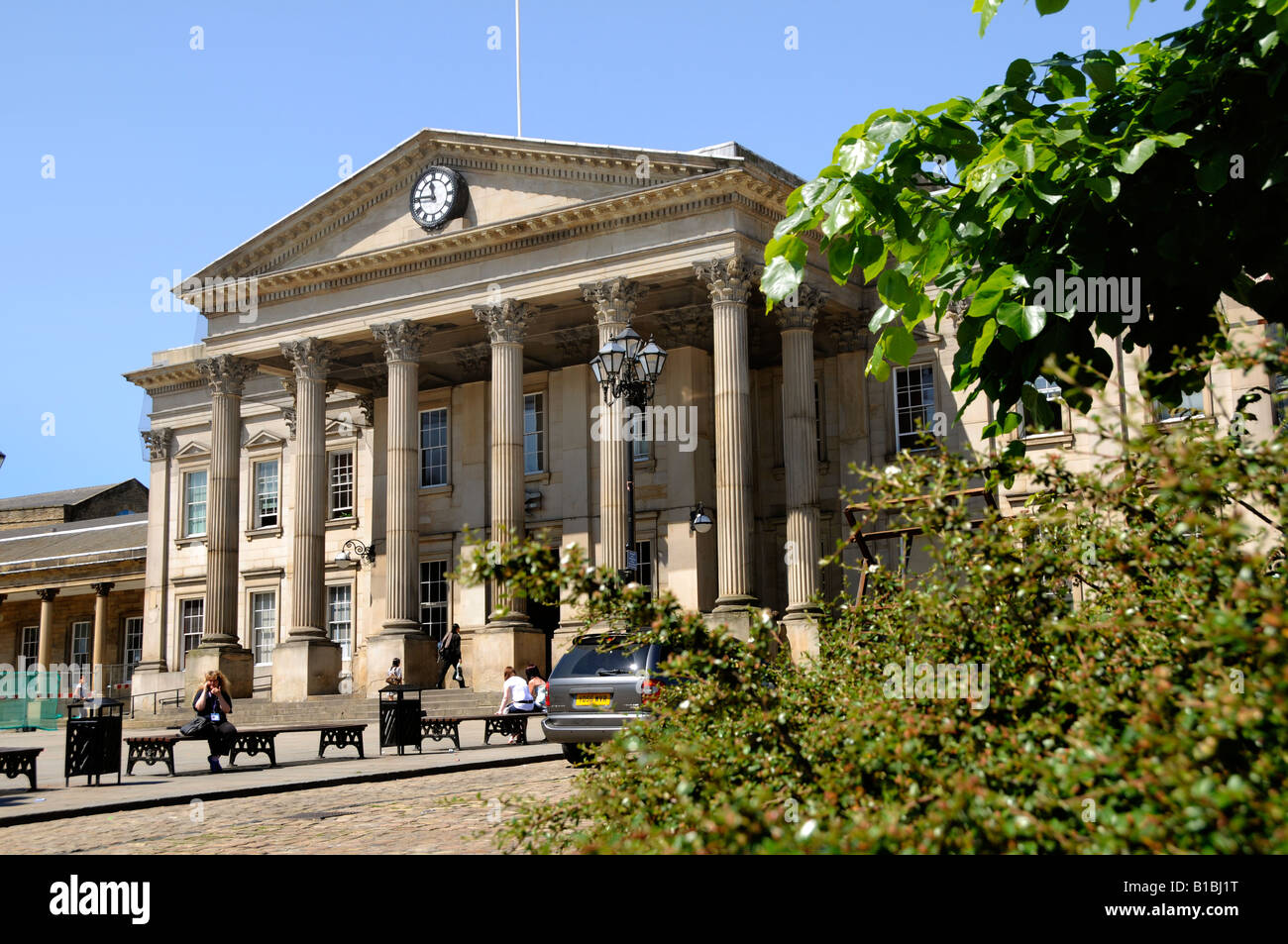 Il colonnato classico e il portico del grande entrata del Vittoriano stazione ferroviaria visto al di là di fogliame a Huddersfield Foto Stock
